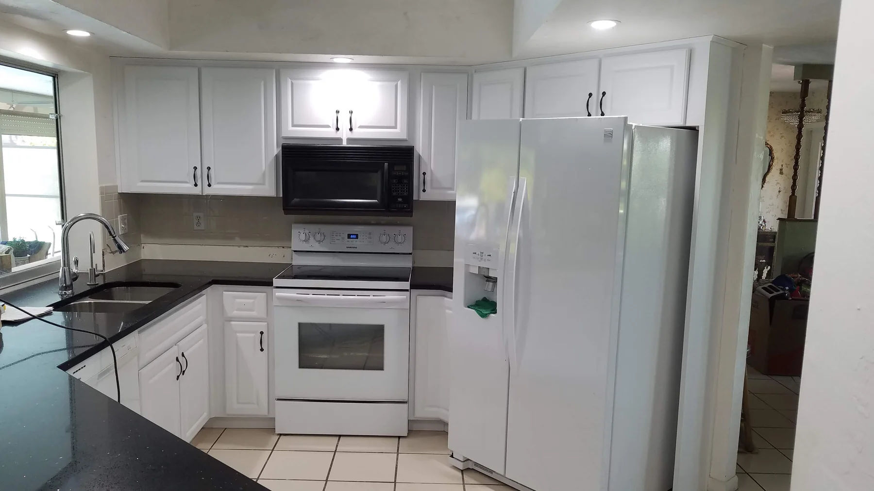 White kitchen cabinet fronts with black counters and black curved pulls
