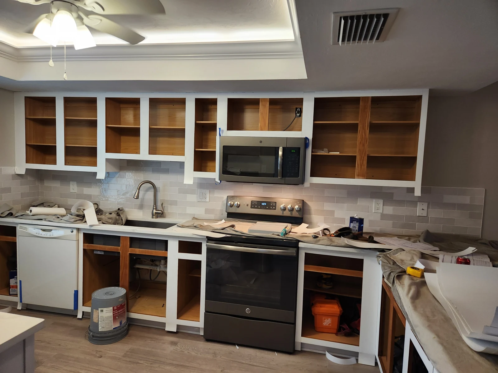 Cabinet boxes with doors removed during refacing, showing retained shelving and prepared face frames