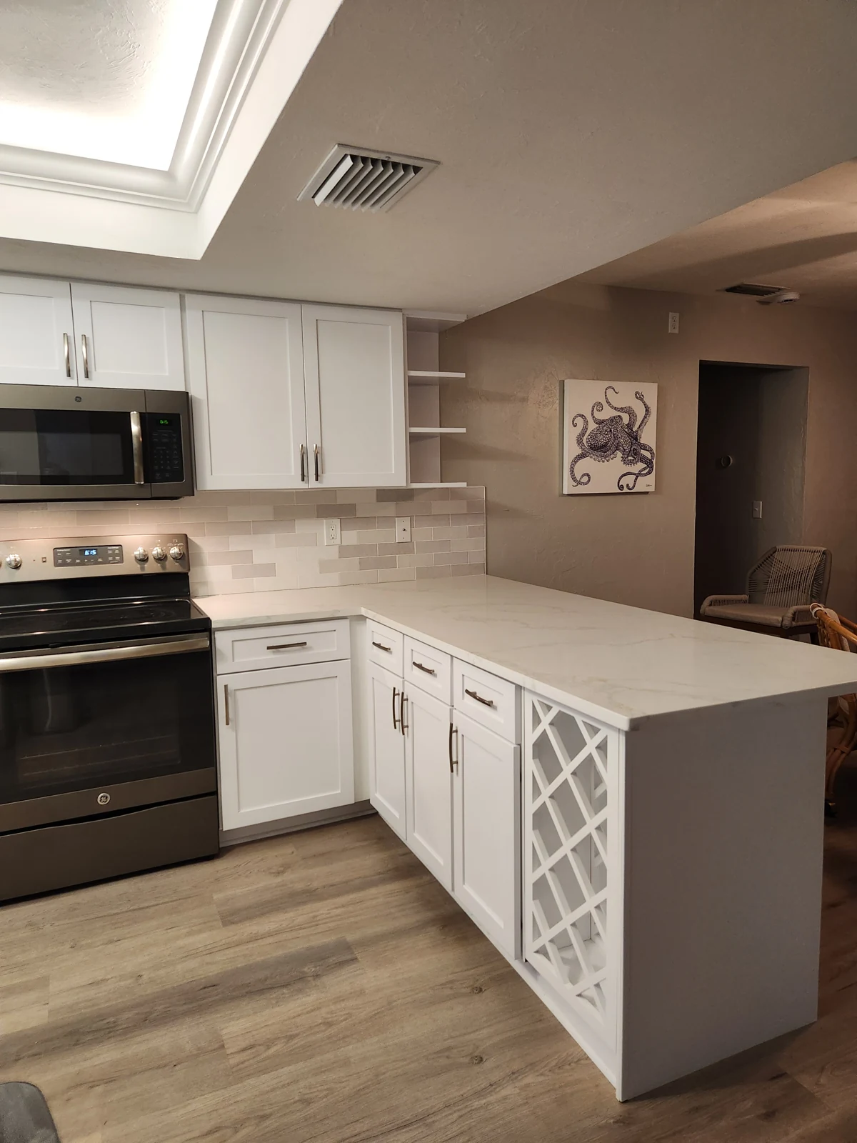 Refaced white cabinet doors and drawers beside an open storage section at the end of a peninsula