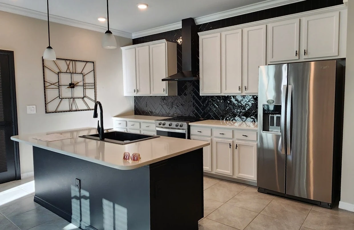 The kitchen before the update, with raised-panel cream cabinet doors and dark bar pulls